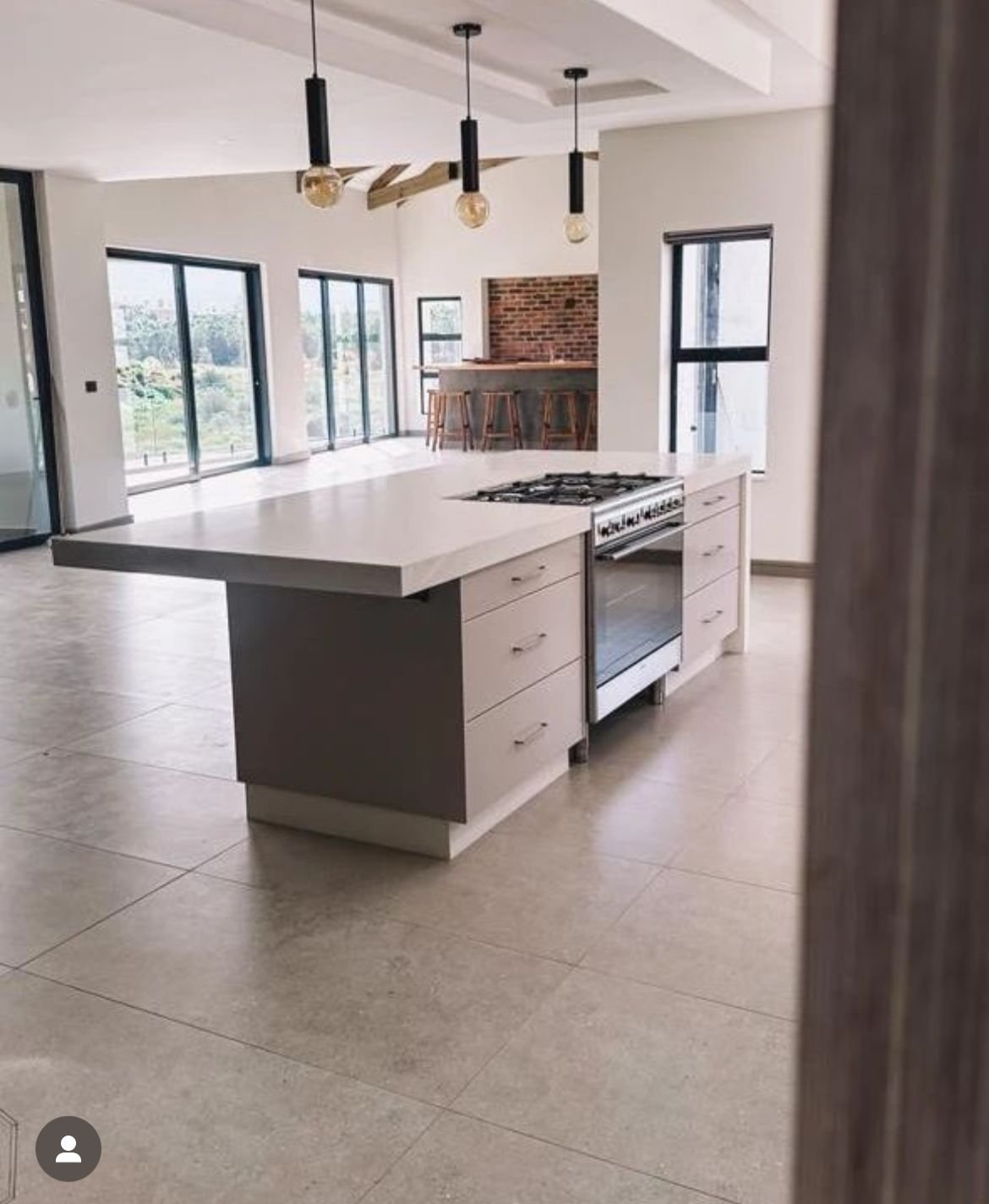An open-plan kitchen with a concrete-topped island and a view through to a brick bar