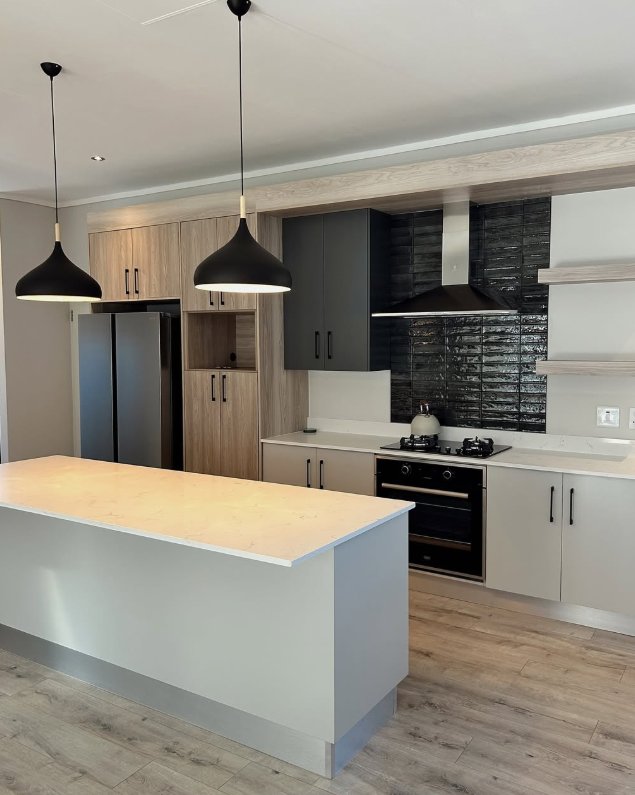 A modern kitchen with grey shaker cabinetry and a black brick splashback