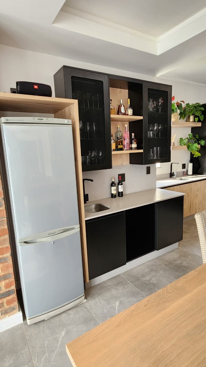 A custom bar with glass-fronted black cabinets, oak interior shelving and a stocked bottle display