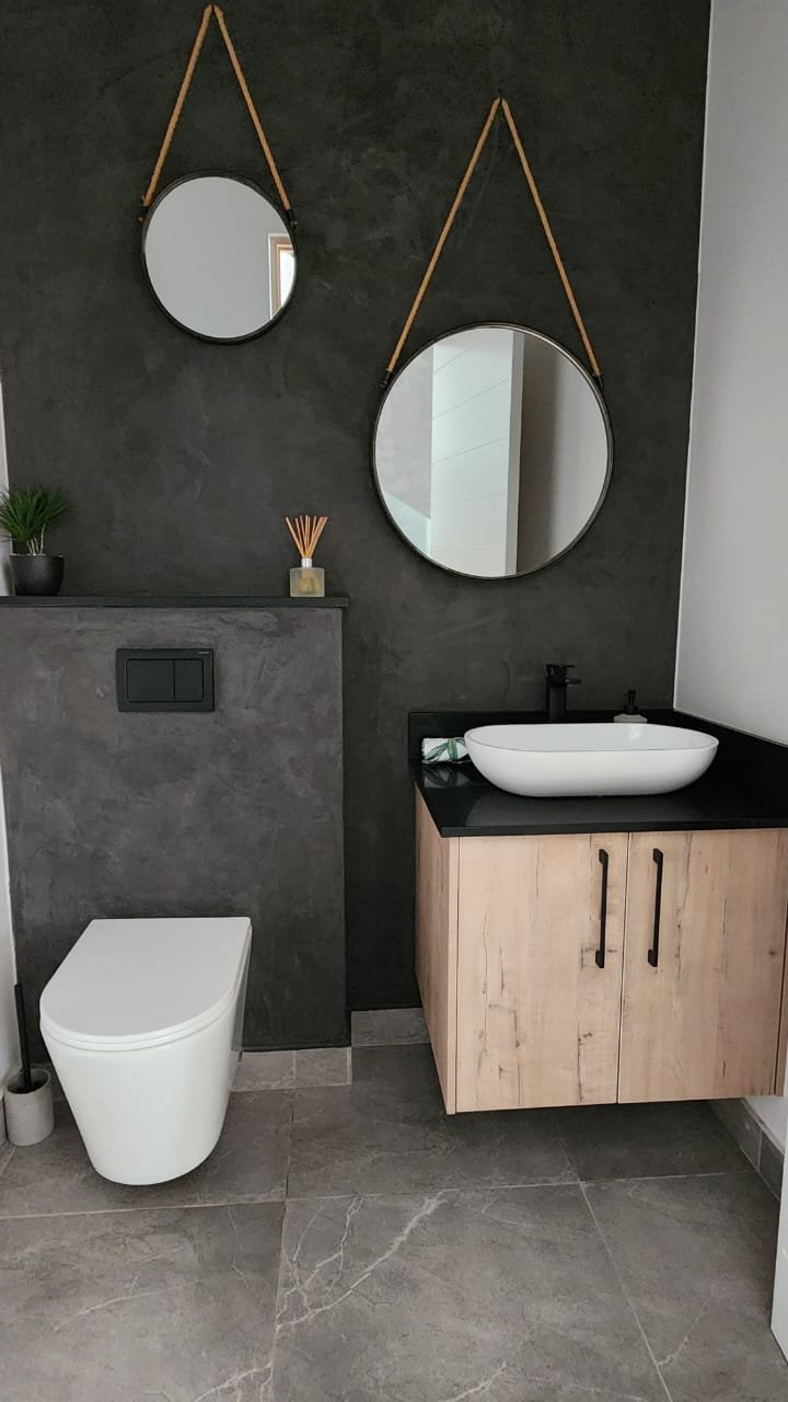 Bathroom with floating oak vanity, round rope mirrors and a dark plaster feature wall