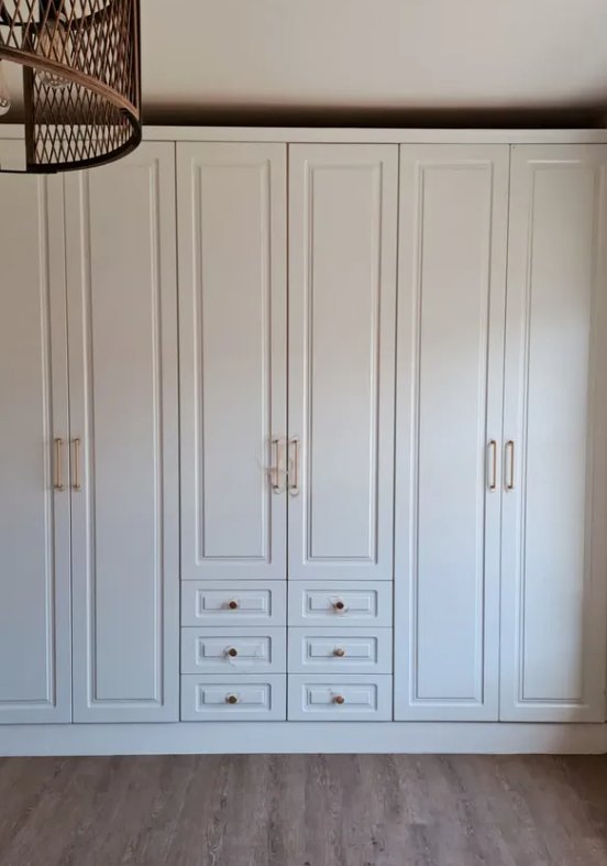 Fitted wardrobe with paneled doors and integrated drawers in soft cream finish